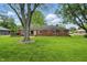 Backyard with brick house, lawn, mature trees, and privacy fence at 8752 Washington Blvd E Dr, Indianapolis, IN 46240