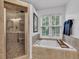 Bright bathtub and tiled surround next to tiled walk-in shower with glass door at 8973 Carnation Dr, Noblesville, IN 46060