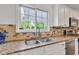 Close-up of kitchen sink and window, showcasing granite countertops, tile backsplash, and stainless steel appliances at 8973 Carnation Dr, Noblesville, IN 46060