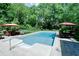 Outdoor in-ground pool with beautiful surroundings including mature trees and patio furniture at 9154 Sargent Manor Ct, Indianapolis, IN 46256