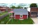 Quaint red home with a gray roof and white trim, set against a backdrop of lush greenery at 104 W Pearl St, Trafalgar, IN 46181