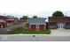 Charming red home exterior with a cozy porch, nestled near a brick building and green lawn at 104 W Pearl St, Trafalgar, IN 46181