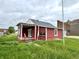 Side view of an exterior of the home with a white-columned covered porch and red horizontal siding at 104 W Pearl St, Trafalgar, IN 46181