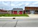 The home featuring red horizontal siding and a gray roof next to a neighboring commercial building at 104 W Pearl St, Trafalgar, IN 46181