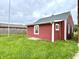 Exterior side view of a red house with horizontal siding, white trim, and a new roof at 104 W Pearl St, Trafalgar, IN 46181