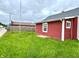 Side view of exterior of single Gathering home featuring red siding, new gray roof and white trim windows at 104 W Pearl St, Trafalgar, IN 46181