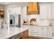 Well-lit kitchen featuring white cabinetry, stainless steel appliances, and a wooden range hood at 10505 Golden Bear Way, Noblesville, IN 46060