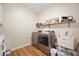 Laundry room with gray washer and dryer, sink, floating shelf, and wood-look floors at 10505 Golden Bear Way, Noblesville, IN 46060