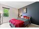 Cozy bedroom with a grey and red bedspread, a dark accent wall, and a window view of trees at 11041 Limbach Cir, Indianapolis, IN 46236