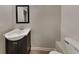 Half bathroom with a dark vanity, sink, mirror, and a toilet at 1305 Gleneagle Dr, Indianapolis, IN 46239