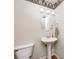 Clean powder room featuring pedestal sink, oval mirror, wallpaper accent, and a modern toilet at 1306 Flat Wood Ct, Brownsburg, IN 46112
