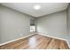 Neutral bedroom showcasing wood-look flooring, light-filtering window shade, white trim, and overhead lighting at 1306 Flat Wood Ct, Brownsburg, IN 46112