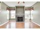 Bright living room featuring hardwood floors, a fireplace, large windows with charming decor and a ceiling fan at 1306 Flat Wood Ct, Brownsburg, IN 46112