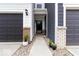 Close-up of a walkway between townhomes, leading to a dark front door with plants and gravel landscaping at 14350 Ludwell Ct, Fishers, IN 46037