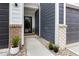 Close-up view of a pathway to a front door, flanked by brick columns, gravel, and colorful potted plants at 14350 Ludwell Ct, Fishers, IN 46037