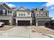 Exterior showcasing a row of townhomes with black garage doors and neutral color schemes under a blue sky at 14350 Ludwell Ct, Fishers, IN 46037