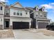 A row of townhomes, featuring varying neutral color schemes and black garage doors, are displayed in the exterior view at 14350 Ludwell Ct, Fishers, IN 46037