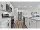 Kitchen with white cabinets, stainless steel appliances, wood-look floors, quartz countertops, and dark hardware at 14350 Ludwell Ct, Fishers, IN 46037