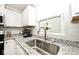 Close-up of stainless steel sink with granite counters and modern faucet under a bright window at 200 Mission Terrace Dr, Whiteland, IN 46184