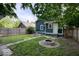 A fenced backyard with a well-maintained lawn, fire pit, and lush greenery offers a private outdoor retreat at 3934 N Kenwood Ave, Indianapolis, IN 46208