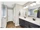 Bathroom with a large mirror reflecting a tile shower, a double sink vanity with dark cabinets, and wood-look flooring at 4602 Hayward Way, Westfield, IN 46062