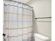 Close-up on a bathroom showing a bathtub with a white shower curtain with colorful stripes and a toilet at 4602 Hayward Way, Westfield, IN 46062
