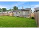 View of the home's backyard, featuring a well-maintained lawn and a wooden fence for privacy at 5473 E 18Th St, Indianapolis, IN 46218