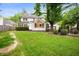 Backyard featuring lush green grass, mature shade trees and patio furniture at 6020 Gladden Dr, Indianapolis, IN 46220