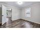 Neutral bedroom featuring wood-look floors, white trim, a window with natural light and an open door at 6045 Dewey Ave, Indianapolis, IN 46219