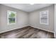 Clean bedroom featuring wood-look floors, neutral walls, white trim, and double windows providing natural light at 6045 Dewey Ave, Indianapolis, IN 46219