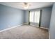 A bright blue bedroom with plush carpet, window with blinds and green drapes, and ceiling fan at 7093 Republic Ln, Indianapolis, IN 46259