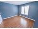 This bedroom features neutral blue walls, laminate flooring, and bright window at 7093 Republic Ln, Indianapolis, IN 46259