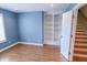 Comfortable bedroom boasts laminate floors, custom built-in shelving, and adjacent staircase at 7093 Republic Ln, Indianapolis, IN 46259