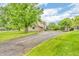 Expansive backyard with a paved driveway, lush greenery, and mature trees at 7633 Janean Dr, Brownsburg, IN 46112