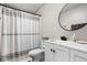 Clean bathroom featuring a toilet, white sink vanity, round mirror, and shower with gray and white curtain at 7990 S County Road 200 E, Pittsboro, IN 46167