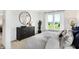 Well-lit bedroom showcasing a black dresser with round mirror and ample natural light at 8684 Marietta Ln, McCordsville, IN 46055