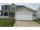 Attached two-car garage on a home with a porch and tan siding at 8939 Newchurch Blvd, Indianapolis, IN 46231