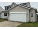 A two-car garage is attached to a house with tan vinyl siding and black shutters at 8939 Newchurch Blvd, Indianapolis, IN 46231