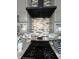 Close-up of a kitchen with black gas range, stylish backsplash, and modern exhaust fan at 1001 Harlan St, Indianapolis, IN 46203
