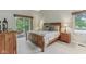 Cozy bedroom with a floral bedspread, wooden furniture, and a door leading to an outdoor balcony overlooking the trees at 10759 Sawgrass Dr, Fishers, IN 46037
