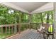 Relaxing screened porch with wood floors and railings and a wicker chair overlooking lush trees at 10759 Sawgrass Dr, Fishers, IN 46037