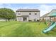 Expansive backyard featuring lush green grass, a playset, and a black chain link fence at 11072 Lake Run Dr, Fishers, IN 46038