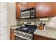 Kitchen featuring stainless steel stove and microwave, granite countertops, and wood cabinets at 11510 Monon Farms Ln, Carmel, IN 46032