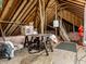 View of unfinished attic showing the roofline, wooden supports, pink insulation, and storage containers at 13069 Abraham Run, Carmel, IN 46033