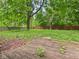 Backyard featuring a deck, overgrown vegetation, a wooden fence, and mature trees at 1325 Northcrest Dr, Anderson, IN 46012