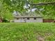 Image of the backyard showcasing the home's exterior and a green lawn partially shaded by mature trees at 1325 Northcrest Dr, Anderson, IN 46012