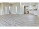 Open-concept living area showcasing gray laminate flooring leading to a well-lit kitchen with white cabinetry at 1325 Northcrest Dr, Anderson, IN 46012