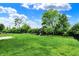 Expansive backyard with a grassy lawn, playset, and mature trees under a sunny, partly cloudy sky at 1384 Horse Shoe, Greenwood, IN 46143