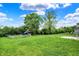 Lush backyard featuring a playset, well-maintained lawn, and mature trees under a sunny, partly cloudy sky at 1384 Horse Shoe, Greenwood, IN 46143