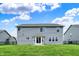 The backyard features a grassy lawn, a home with light gray siding and a white patio at 1384 Horse Shoe, Greenwood, IN 46143